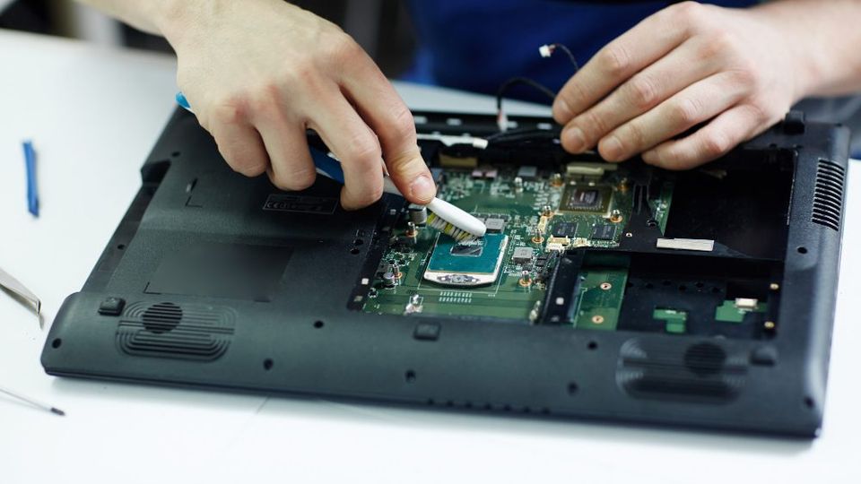 Technicien ouvrant le châssis d'un ordinateur portable en fin de contrat