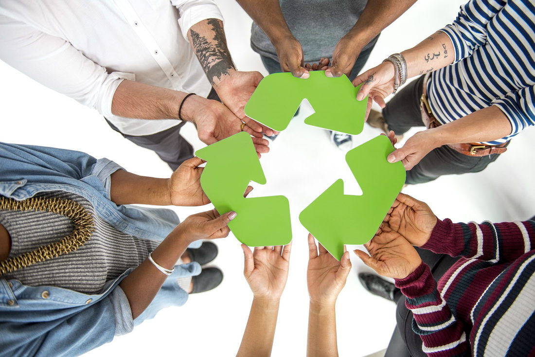 Mains de plusieurs personnes réunies autour d'un symbole de recyclage vert